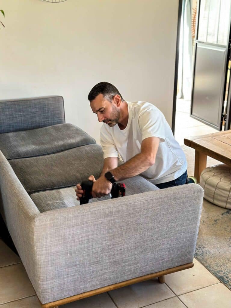 Technicien nettoyant un canapé gris avec une brosse mécanique